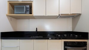 Uma cozinha equipada com micro-ondas, fogão, pia e armários.