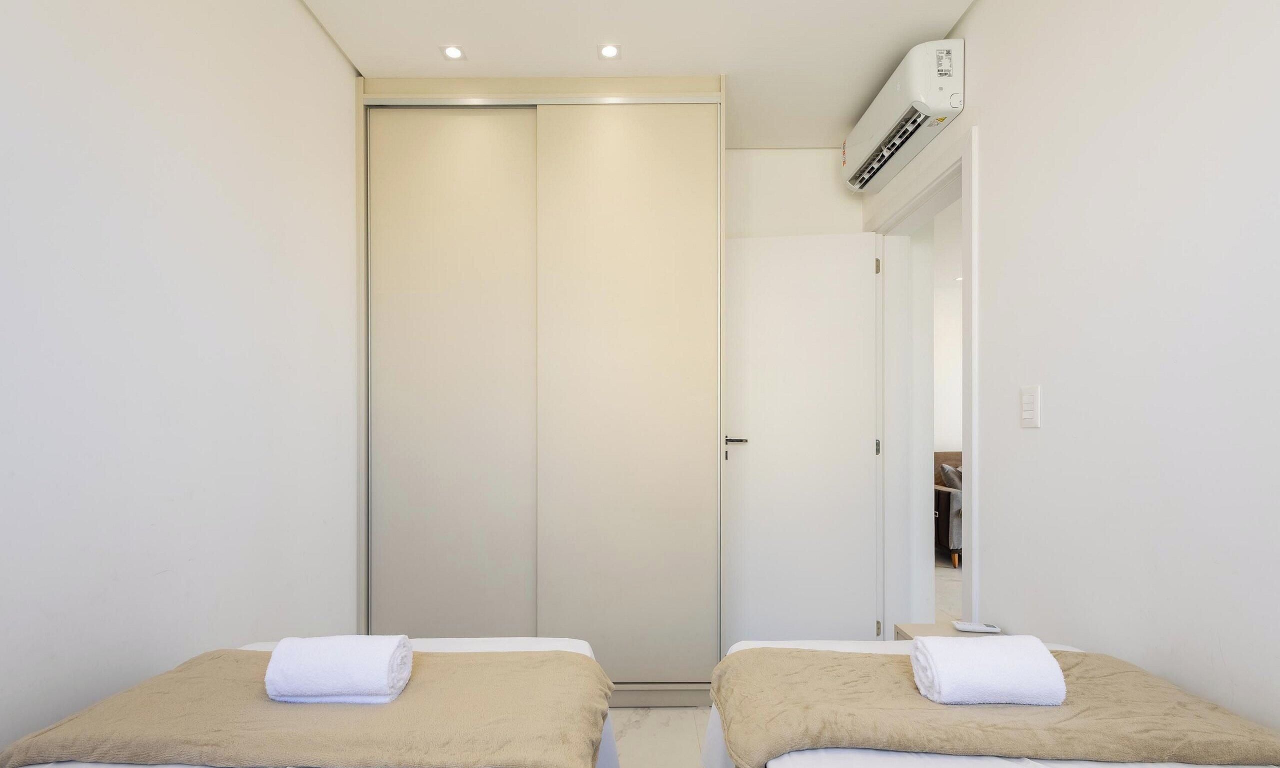 Una habitación de hotel con cama, espejo, equipo de aire acondicionado y armario.