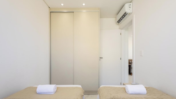 Quarto de hotel com cama, espelho, ar condicionado e guarda-roupa.