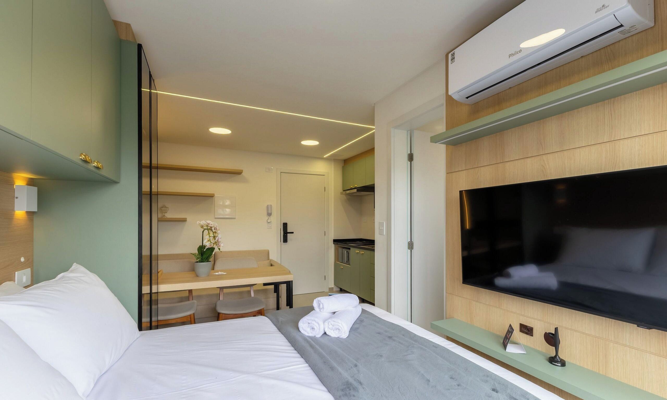Ein Hotelzimmer mit Bett, Schreibtisch, Fernseher und Klimaanlage.