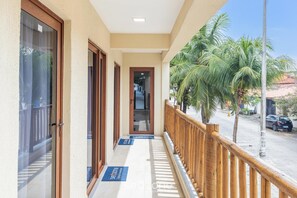 A hotel corridor with wooden doors, a balcony with a wooden railing, and a palm tree outside. - Modern Apartment, 160 m From Cumbuco Beach Mcu0103 (Caucaia)