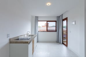 A kitchen with a window, a sink, and a door leading to a balcony. - Apt 1 Bedroom 160m Beach Ed Cumbuco Real Mcu0203 (Caucaia)