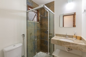 A bathroom with a glass shower enclosure, a toilet, a sink with a marble countertop, and a mirror. - Apt 1 Bedroom 160m Beach Ed Cumbuco Real Mcu0203 (Caucaia)