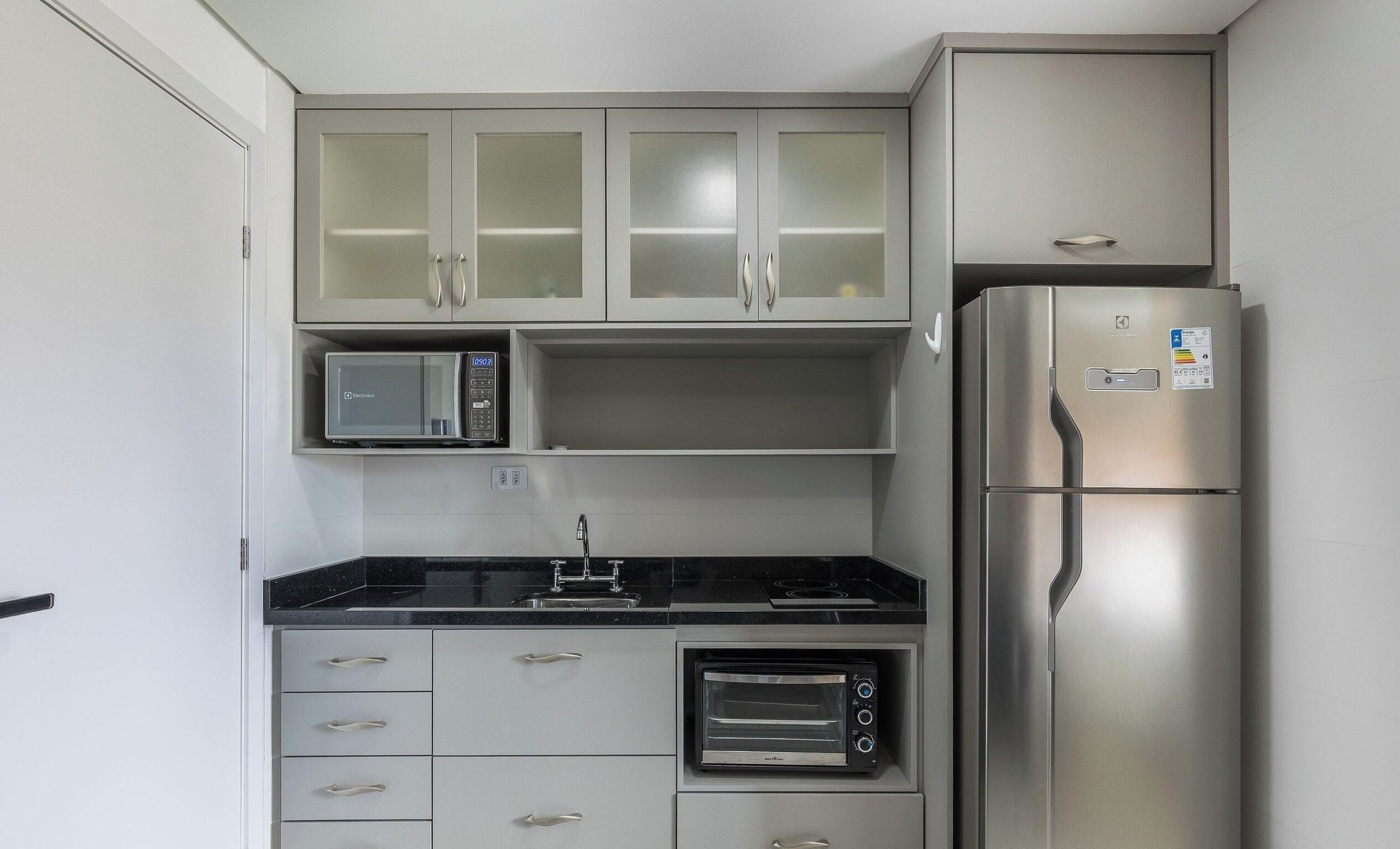 A compact kitchen with a microwave, stove, oven, and refrigerator.