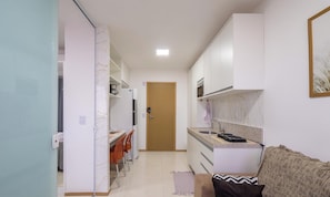 A compact kitchen with a dining area, a microwave, a stove, and a small refrigerator. - Apt 500m fr/ the sea in a Build. w/ Pool Hpa0606 (Salvador)