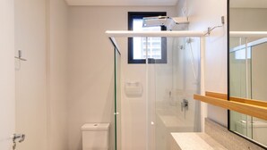 A modern bathroom with a glass shower enclosure, a toilet, and a vanity with a mirror. - Apto w/ 3 En-suites, BBQ & Ocean View Rih0203 (Porto Belo)