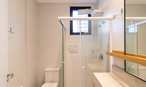 Une salle de bain moderne avec une douche à parois de verre, des toilettes et un meuble-lavabo avec un miroir.