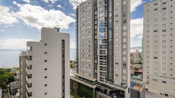 A high-rise residential building with multiple balconies and a view of the sea.