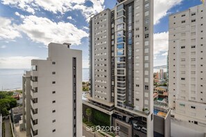 A high-rise residential building with multiple balconies and a view of the sea.