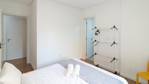 Un dormitorio con cama, perchero y puerta.