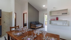 A dining area with a wooden table set for a meal, a sofa, and a view of the outdoors. - Apt in Condo w/ Pool 500m From the Beach Enl0002 (Porto Seguro)