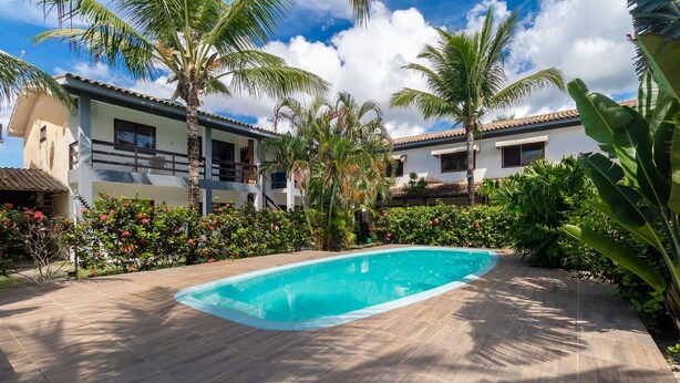A swimming pool surrounded by lush greenery and a multi-story building with balconies. - Apt in Condo w/ Pool 500m From the Beach Enl0002 (Porto Seguro)