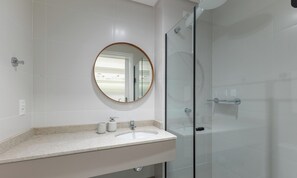 A modern bathroom with a glass shower enclosure, a round mirror, and a white sink with a countertop. - Studio in Build. w/ gym in the City Center Emw1520 (Curitiba)