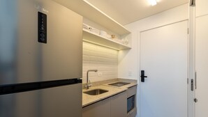 Uma cozinha compacta com geladeira de aço inoxidável, uma pia dupla e micro-ondas.