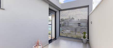 A modern building with a glass door, potted plants, and a tiled floor.