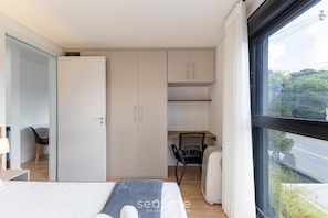 A modern bedroom with a bed, a desk, and a wardrobe. - 1BR apt w/ BBQ in Curitiba Pla0201 (Curitiba)