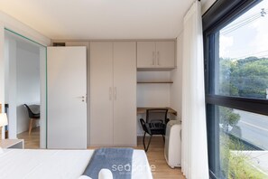 A modern bedroom with a bed, a desk, and a wardrobe. - 1BR apt w/ BBQ in Curitiba Pla0201 (Curitiba)