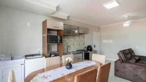 Ett kompakt bostadsutrymme med en matplats, ett litet kök och en soffa.