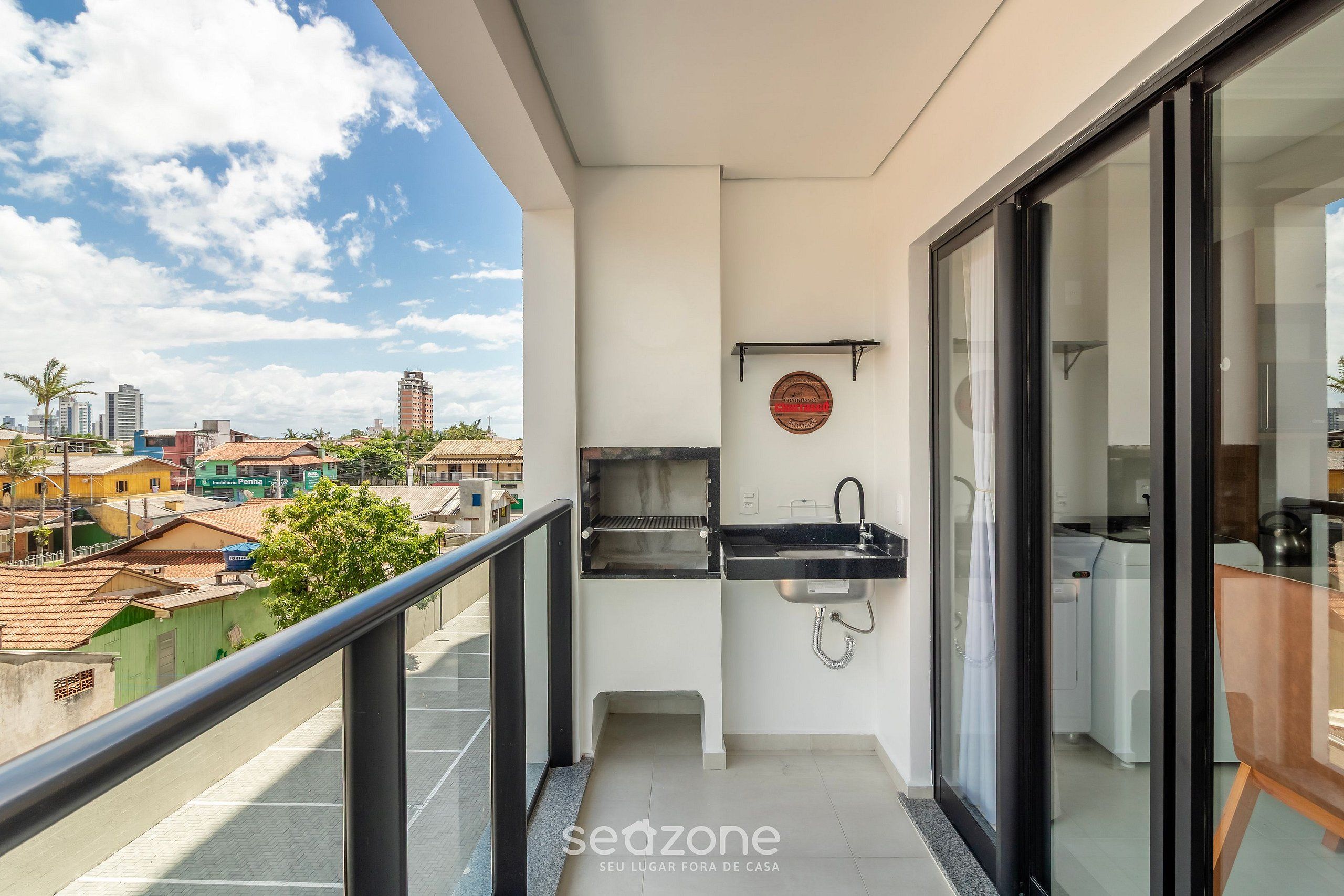 A balcony with a built-in grill, a sink, and a view of the cityscape.