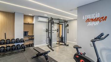Uma academia com equipamentos de musculação, halteres e máquinas de cardio.
