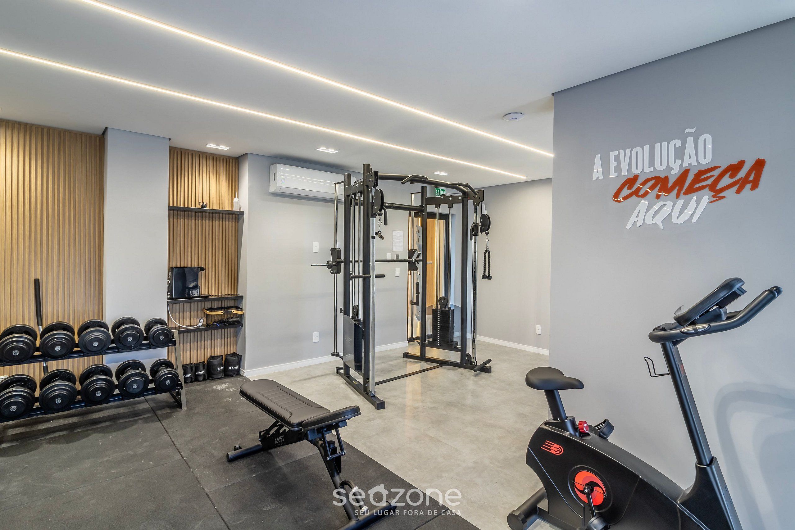 Un gimnasio con equipo de levantamiento de pesas, mancuernas y máquinas de cardio.