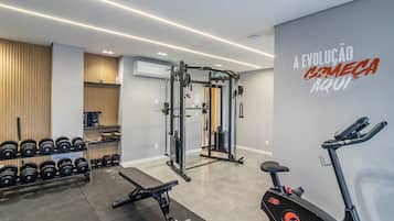 Un gimnasio con equipo de levantamiento de pesas, mancuernas y máquinas de cardio.