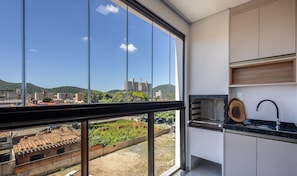 A modern kitchen with a large window, a sink, and a wooden cutting board. - Apt 650m fr/ Beto Carrero in Cond w/ Pool Lav0401 (Penha)