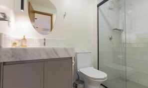 Ein modernes Badezimmer mit einem мраморный Waschbecken, einer Toilette und einer Duschkabine.