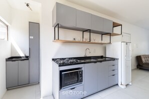 A modern kitchen with grey cabinets, a black countertop, a built-in oven, and a white refrigerator. - Spacious Apartment 200m From the sea Psd201 (Florianópolis)