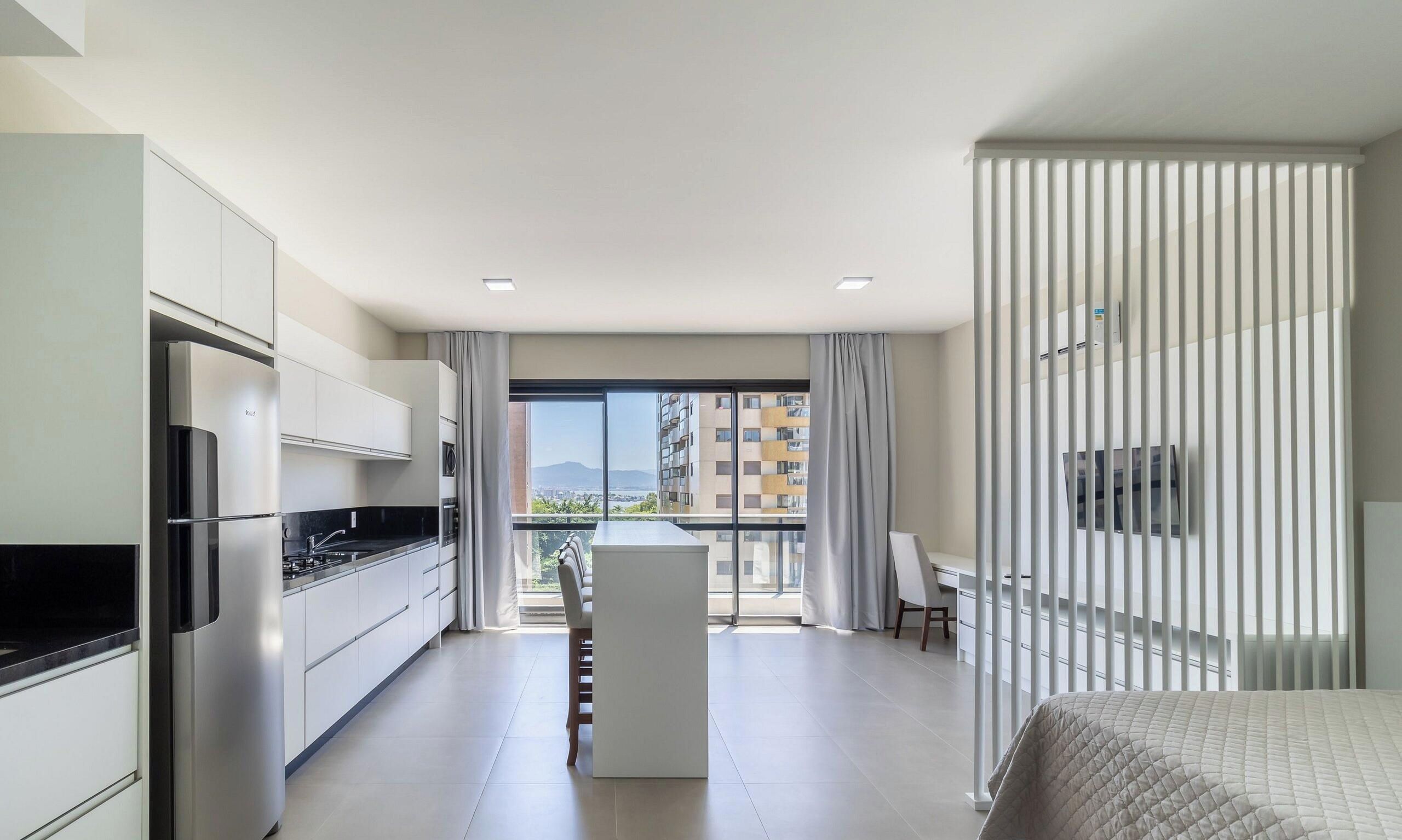 A modern apartment with a kitchen, dining area, and a balcony with a city view.