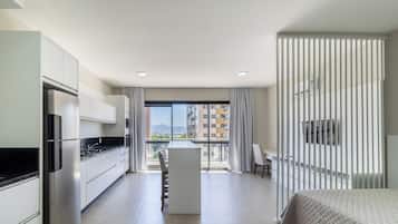 A modern apartment with a kitchen, dining area, and a balcony with a city view.
