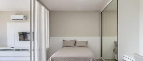 A bedroom with a bed, a wardrobe, a television, and a mirror.