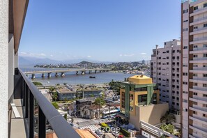 Um edifício alto com vista para uma ponte sobre a água, paisagem urbana e um edifício com telhado verde ao primeiro plano.