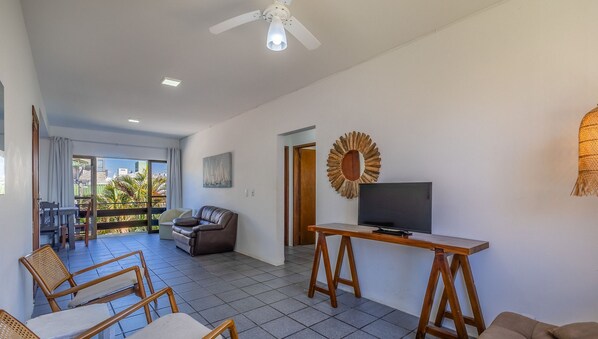 A spacious living area with a television, seating, and a balcony with a view. - Well Located 200m From the sea in Jurere Psd301 (Florianópolis)