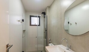A modern bathroom with a glass-enclosed shower, a round mirror, and a white sink. - Apt w/ Balcony 300m From the Beach - Eep0801 (Guarapari)