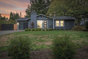 A modern two-story house with a garage, a front door, and a small porch with chairs. - 3-Bedroom Ranch Home, Private Yard, Long Driveway (Edmonds)