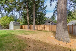 A backyard with a wooden fence, a shed, and a large tree. - 3-Bedroom Ranch Home, Private Yard, Long Driveway (Edmonds)