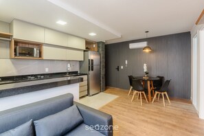 A modern kitchen with a built-in microwave, a refrigerator, and a dining area with a table and chairs. - 1 Bedroom Apartment 300m From the Beach Eep1102 (Guarapari)