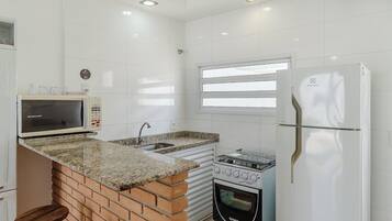 A compact kitchen with a microwave, sink, stove, and refrigerator.