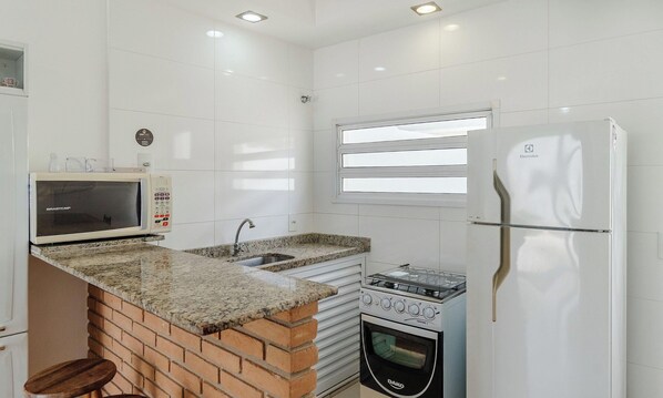 A compact kitchen with a microwave, sink, stove, and refrigerator.