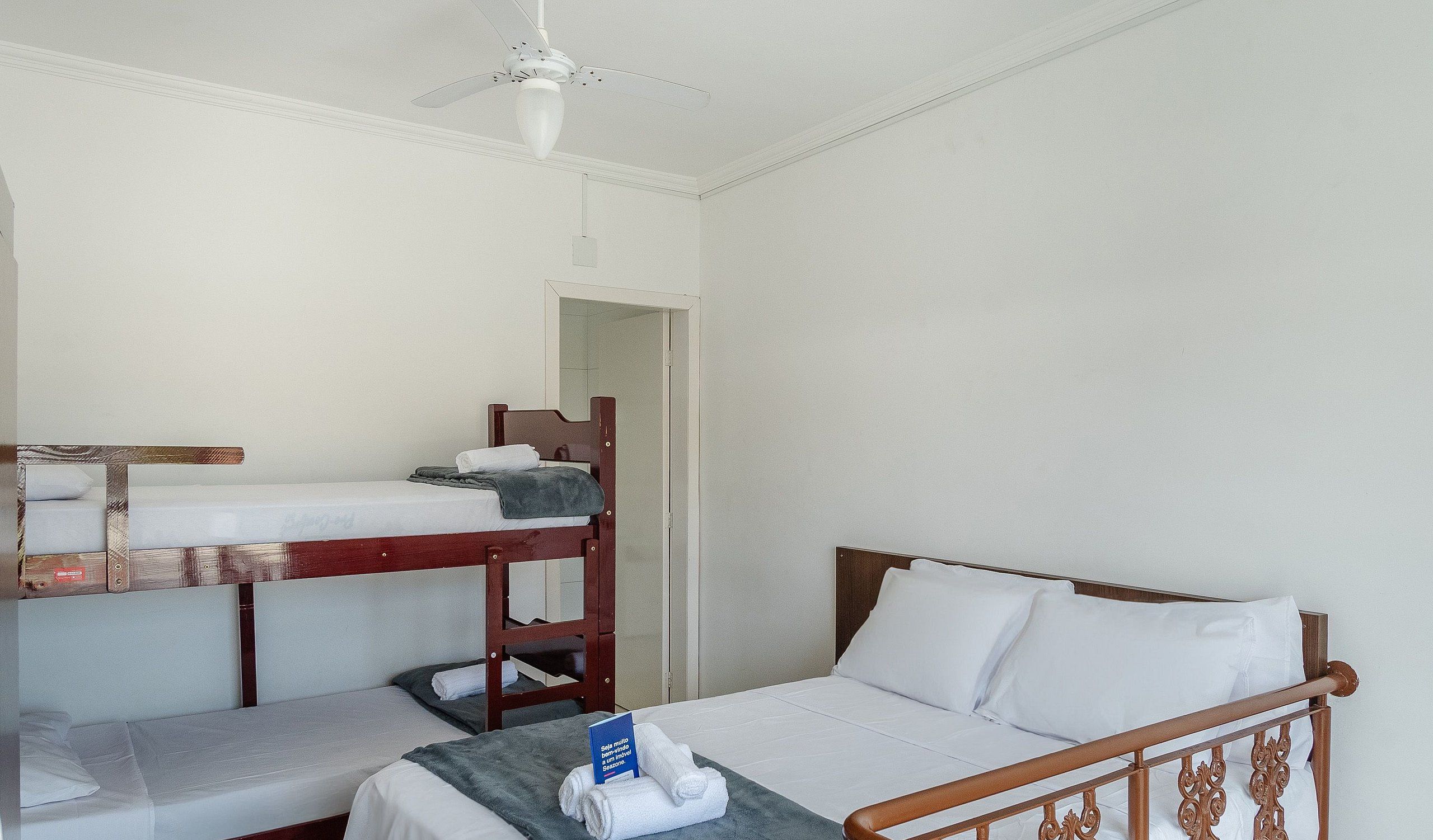 A room with bunk beds, a single bed, and a ceiling fan.
