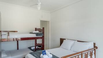 A room with bunk beds, a single bed, and a ceiling fan.