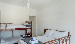 Una habitación con literas, una cama individual y un ventilador de techo.