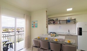 Una cocina con comedor, un balcón con vistas y un refrigerador.