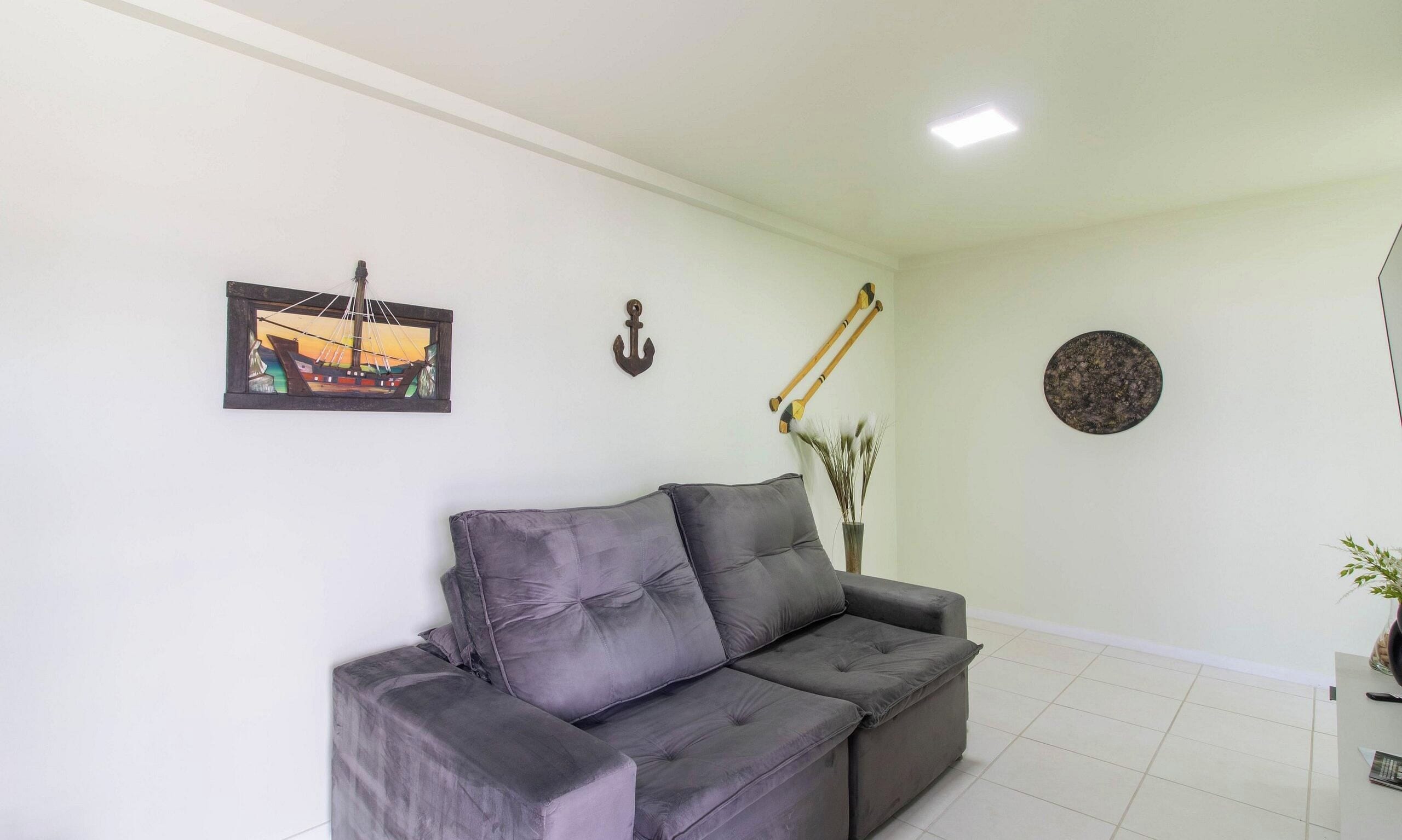 Ein Wohnzimmer mit grauem Sofa, einem gerahmten Gemälde, einer Wandhalterung, zwei Holzstöcken und einer runden Dekotasse.