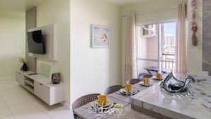 A modern living room with a flat-screen TV, a dining area with a marble table, and a balcony with a view of buildings. - Apart With Barbecue, 210 m From the Beach Csi0706 (Picarras)