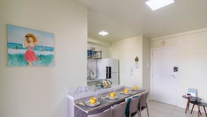 A compact kitchen with a refrigerator, a sink, and a dining area with a table set for two.
