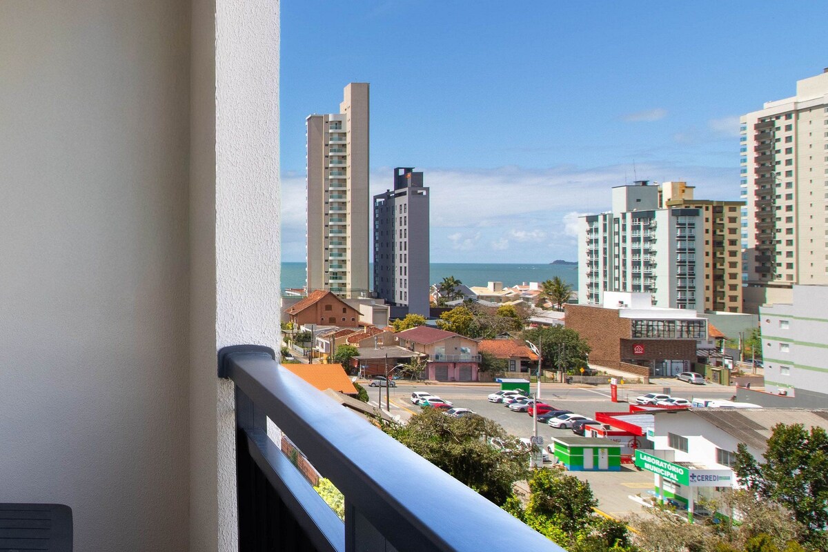 A cityscape with high-rise buildings, a parking lot, and a view of the ocean.