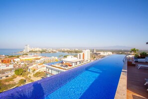 A long swimming pool with a view of a cityscape and the sea. - Soho Skies 204 Stunning Sunset - Ocean Views wit (Puerto Vallarta)