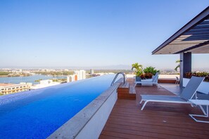 A rooftop infinity pool with a clear view of a cityscape and mountains in the distance. - Soho Skies 204 Stunning Sunset - Ocean Views wit (Puerto Vallarta)